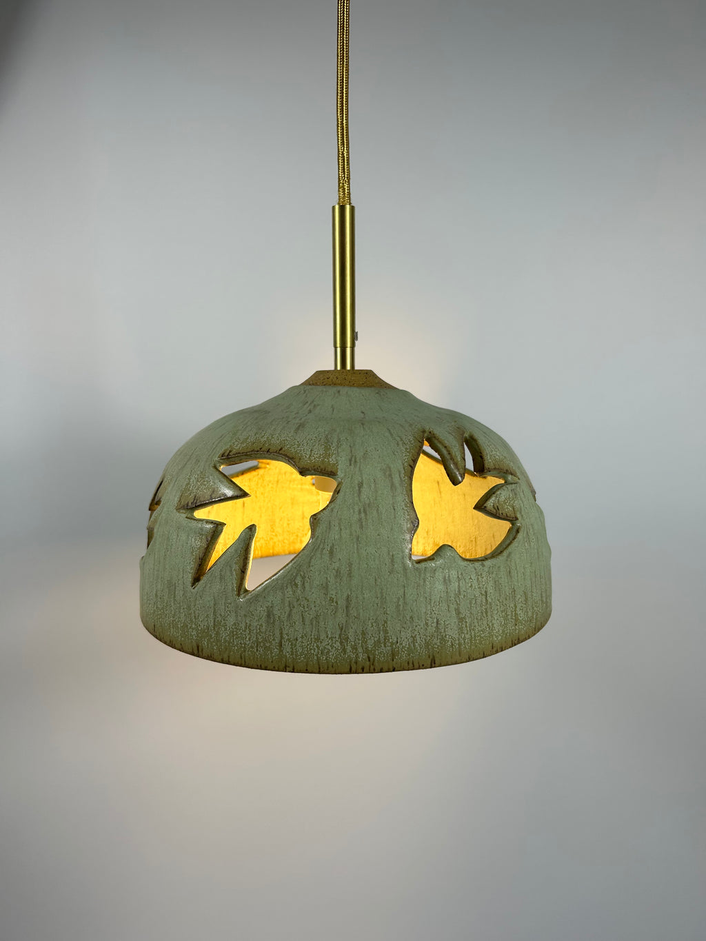 Stoneware green speckled pendant lamp with bird piercings and gold cord 