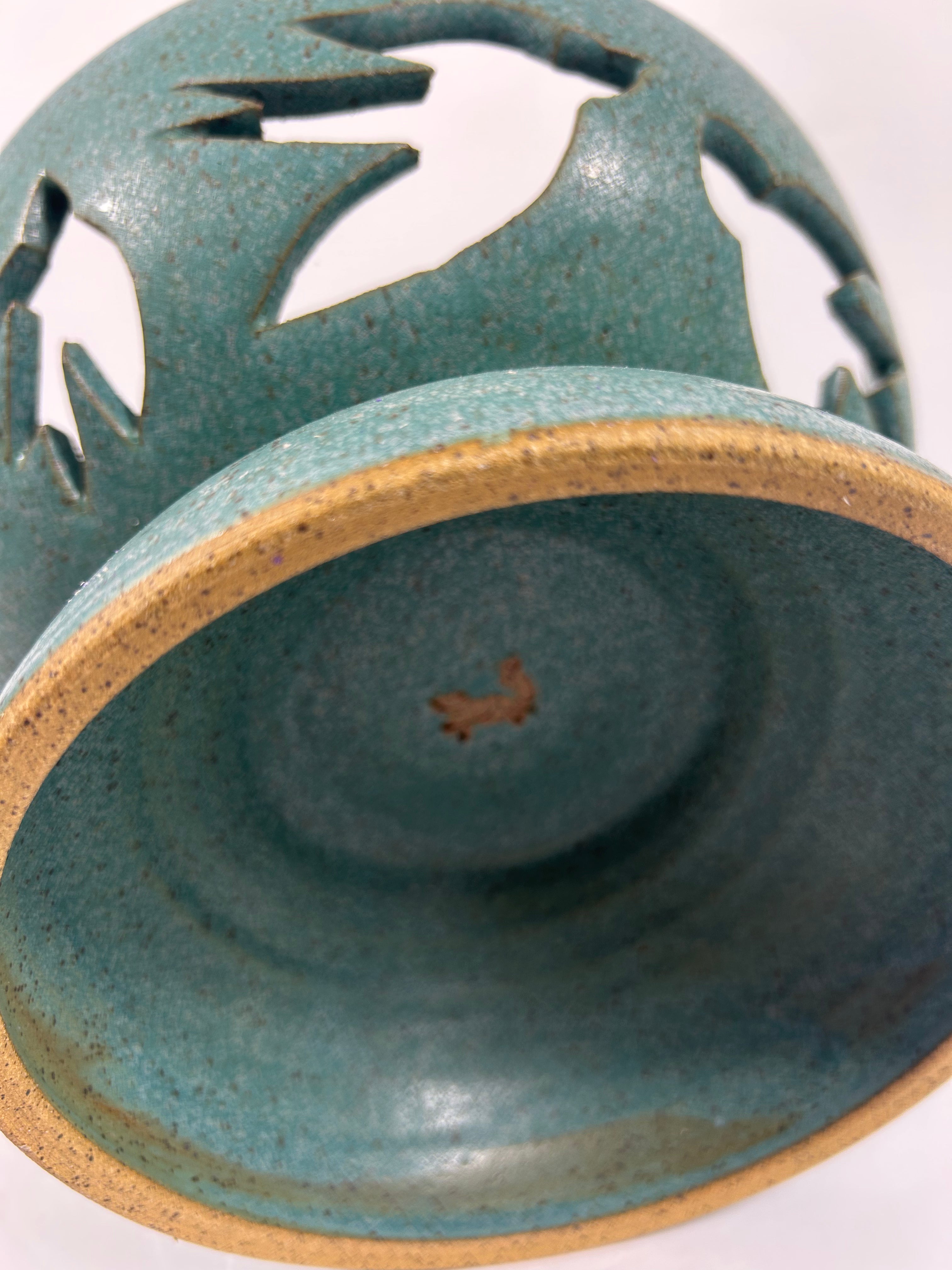 Underside of Stoneware teal pedestal bowl with swallow cut-outs