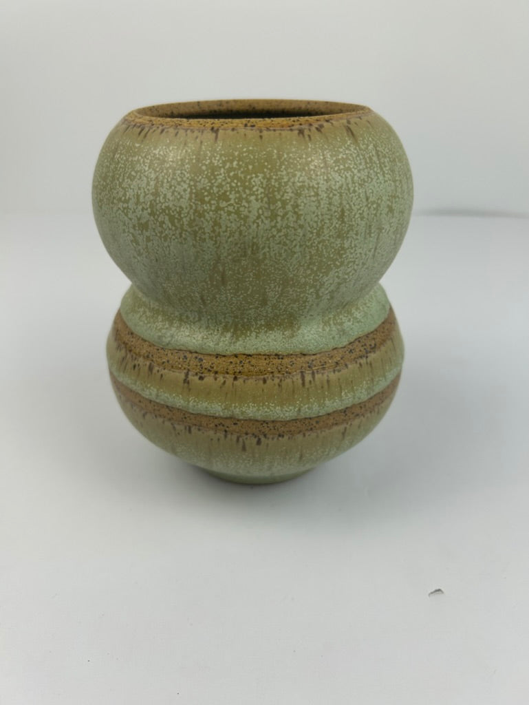A handmade ceramic vase with a distinctive double-bulb shape, featuring a textured sage green glaze with earthy brown and gold-toned accents, set against a plain light gray background.
