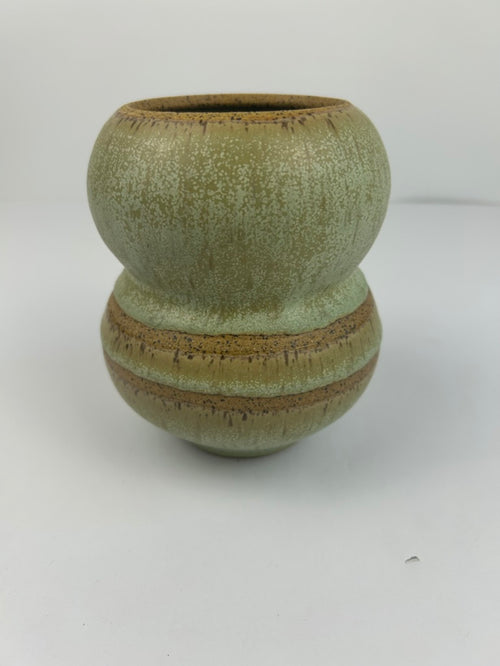 A handmade ceramic vase with a distinctive double-bulb shape, featuring a textured sage green glaze with earthy brown and gold-toned accents, set against a plain light gray background.