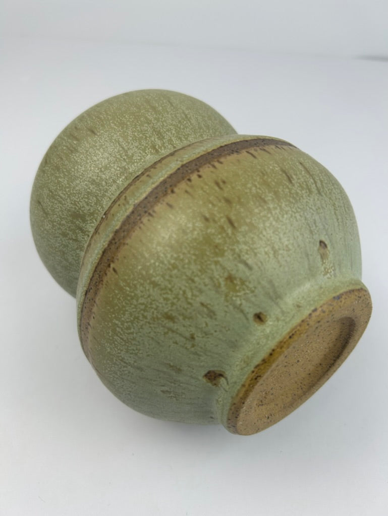 A handmade ceramic vase with a textured sage green glaze and a rustic brown clay band around the center, shown on a plain white background.