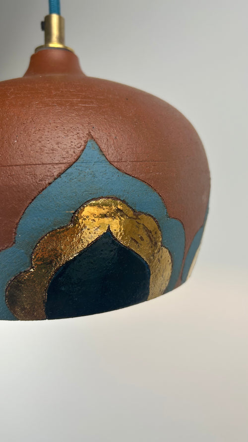 Ceramic pendant light with brown, blue, and gold design on a white background