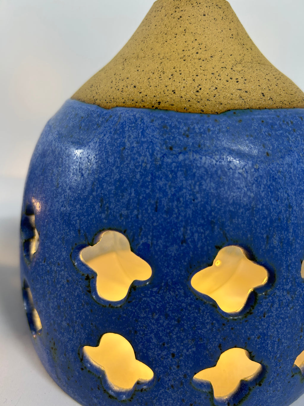 Close up of Cobalt blue ceramic pendant lamp on speckled clay with gold cord and moroccan piercings