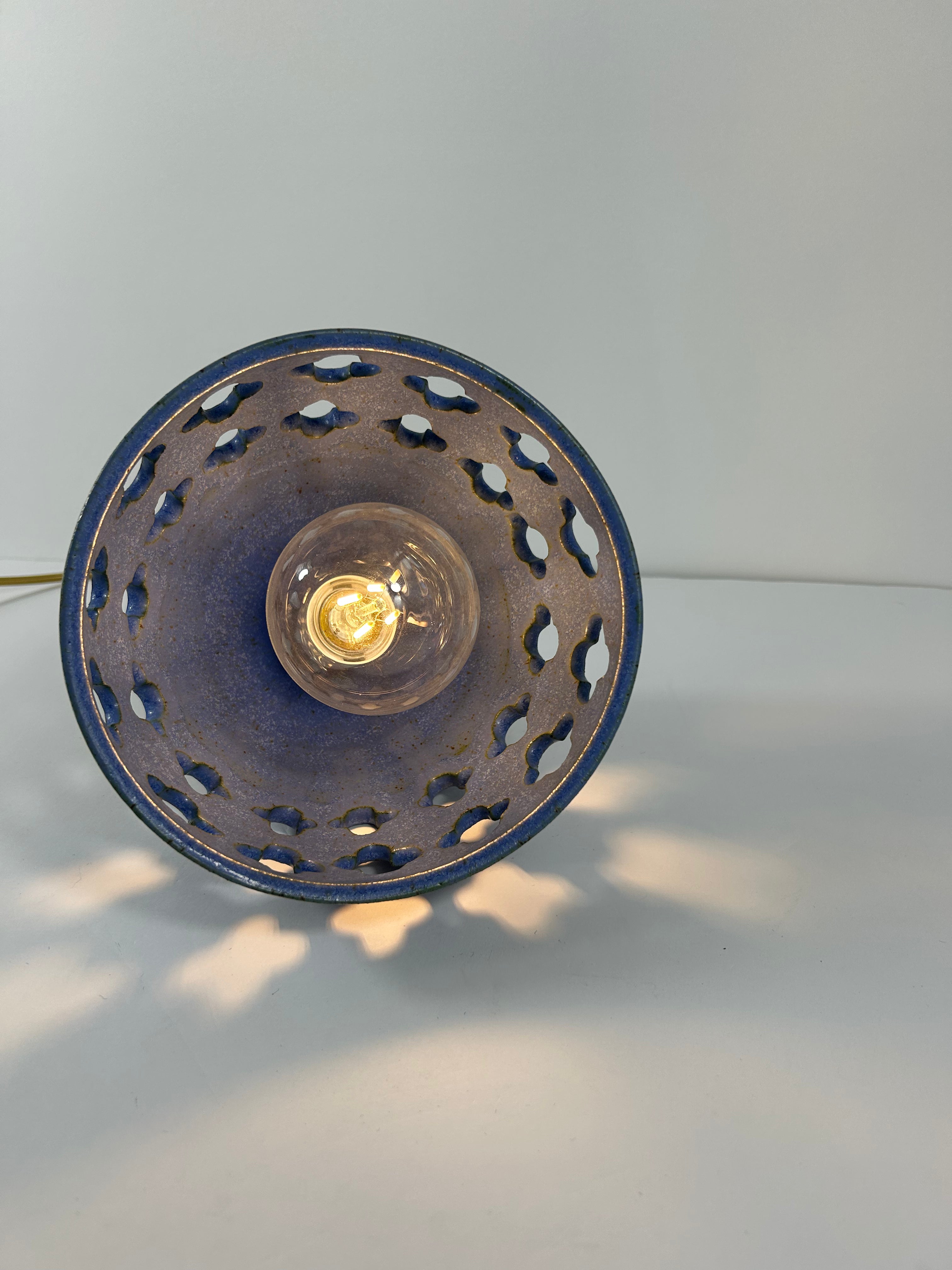 Inside view of Cobalt blue ceramic pendant lamp on speckled clay with gold cord and moroccan piercings