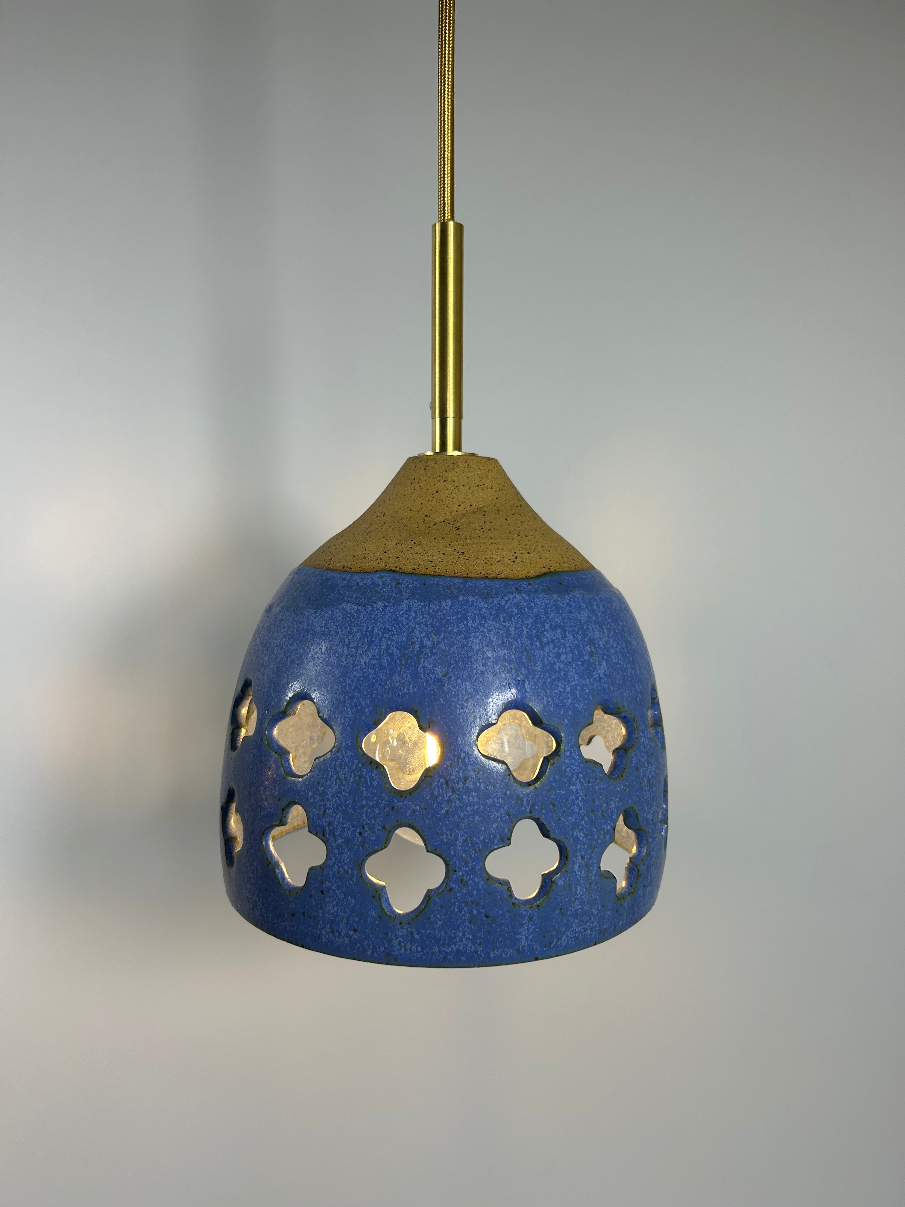Cobalt blue ceramic pendant lamp on speckled clay with gold cord and moroccan piercings